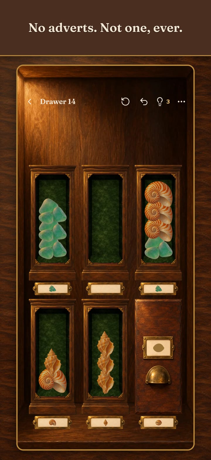 No adverts. Not one, ever. A level of The Shore: sea glass, whelk and nautilus shells in green velvet drawers, one drawer already filed and closed